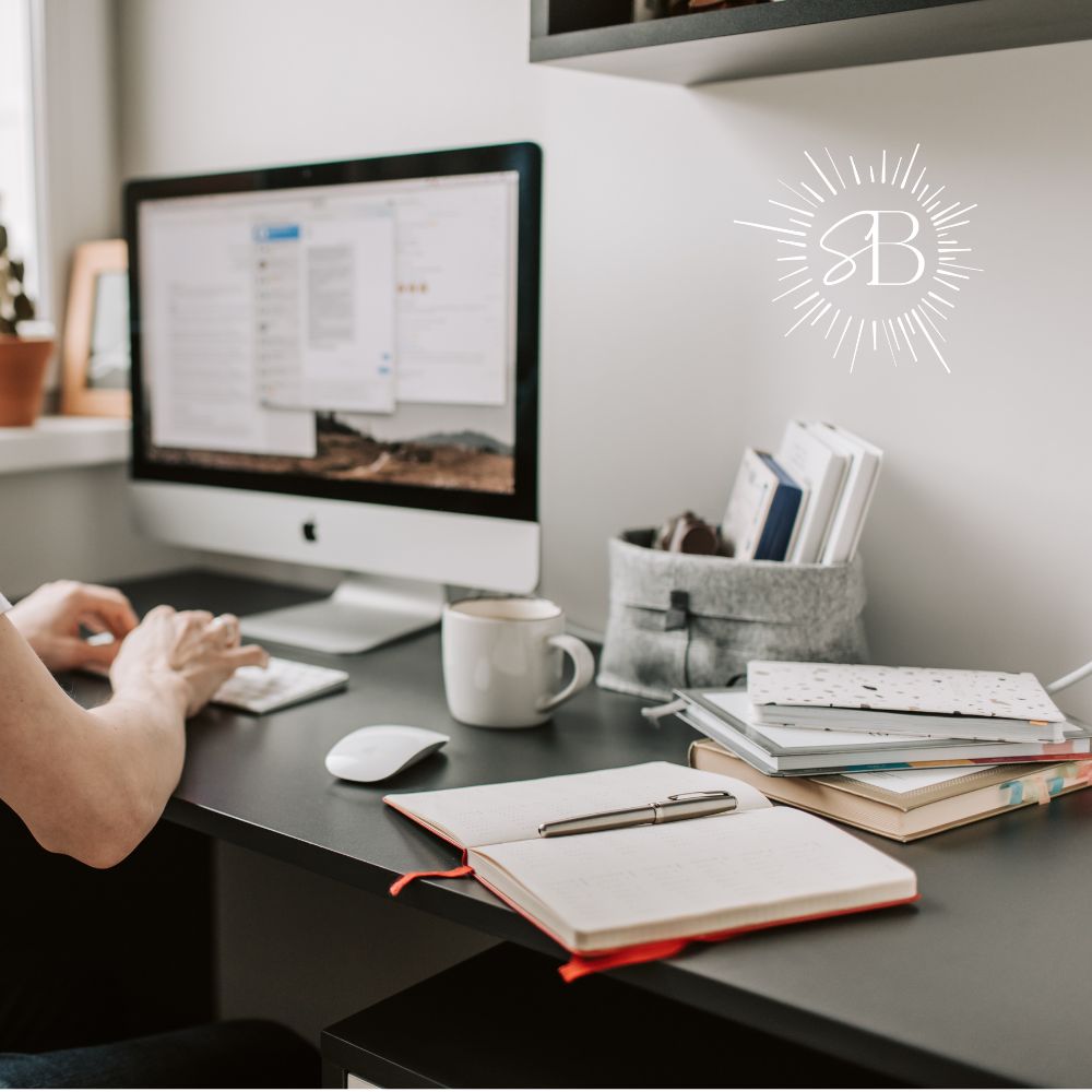 Mac on a desk with notebooks and coffee mug