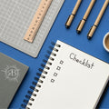 Notebook with 'Checklist' on a blue surface with stationery items