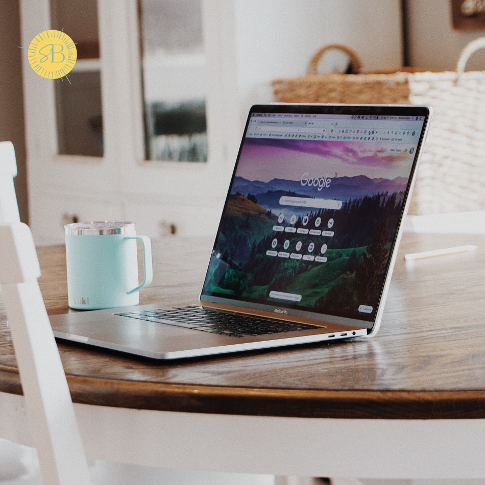 Laptop on a wooden table with a teal mug next to it, in a home setting.